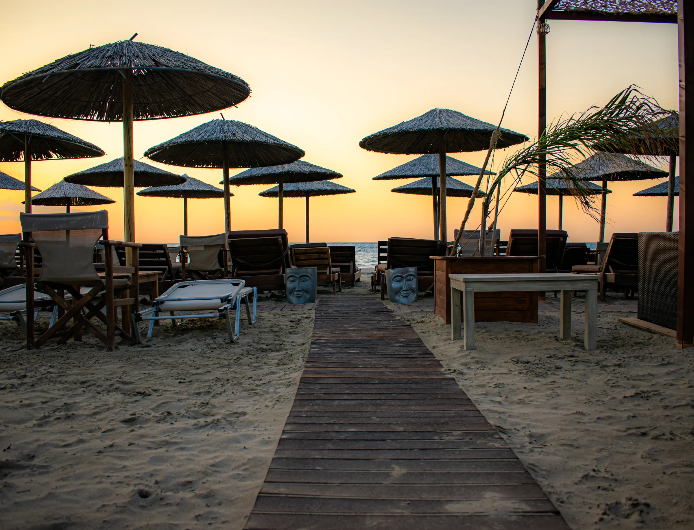 Wooden walkway through Malabar at sunset, with straw umbrellas and the sea ahead